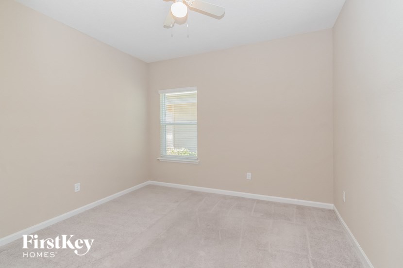 A room with a window and a fan on the ceiling.