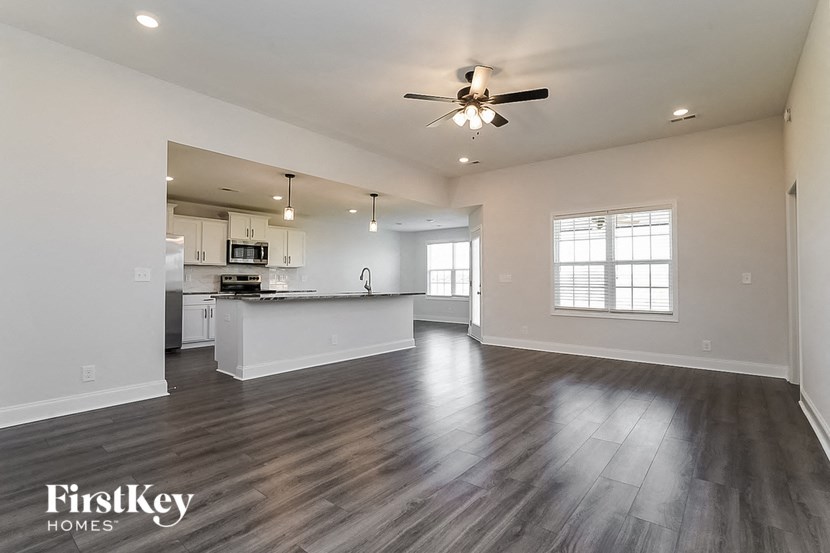 an empty living room and kitchen with a ceiling fan