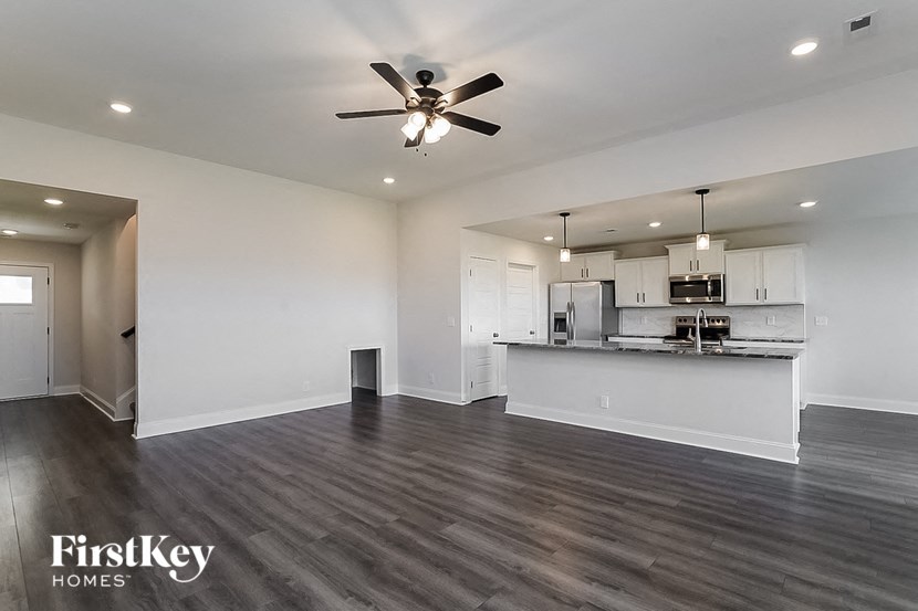 an empty living room and kitchen with a ceiling fan