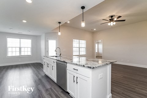 a white kitchen with a counter top and a ceiling fan