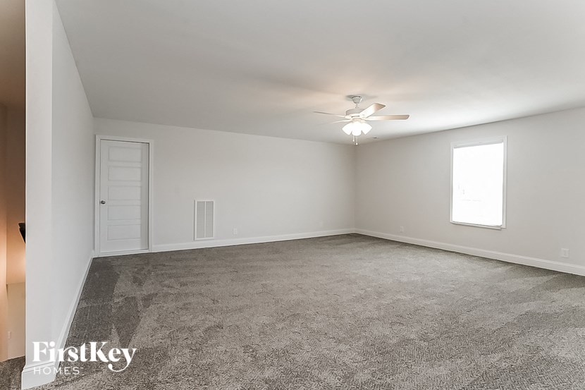 an empty living room with a ceiling fan and a window