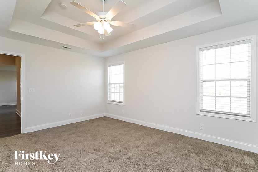 an empty living room with a ceiling fan and two windows