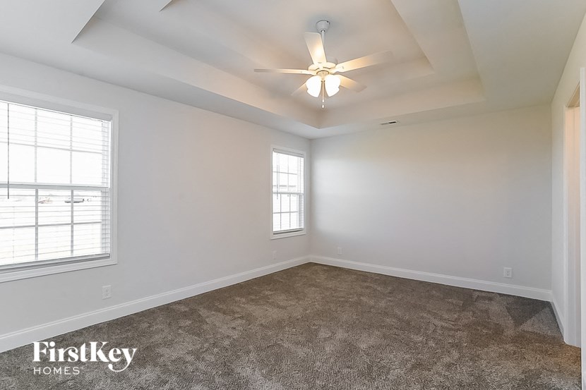 an empty living room with a ceiling fan and a window