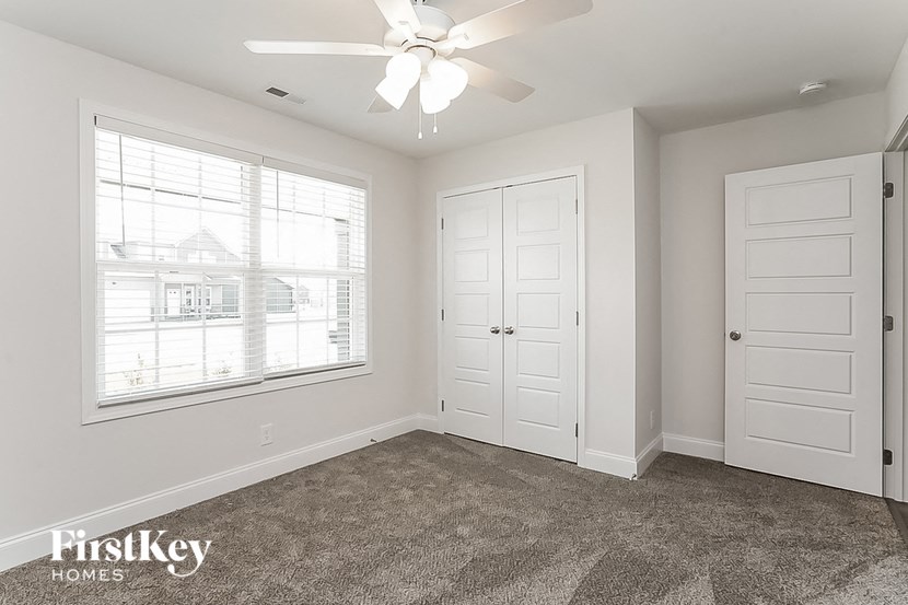 an empty bedroom with a ceiling fan and a window