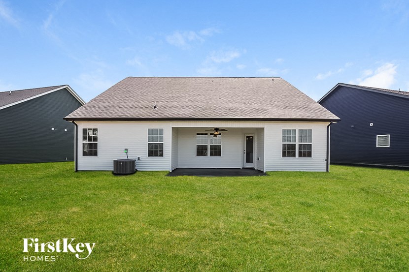 the front of a white house with a grass yard
