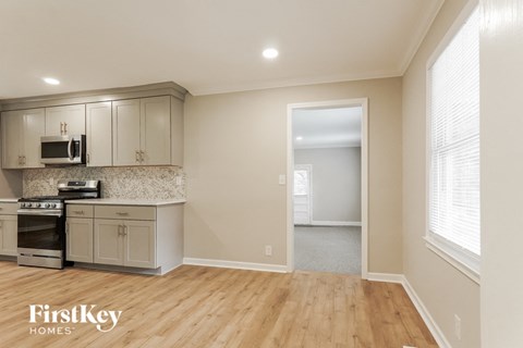 A kitchen with wooden floors and a stove top oven.
