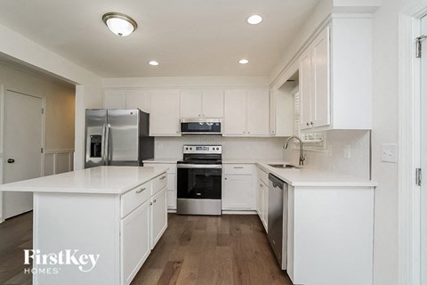 A modern kitchen with white cabinets and stainless steel appliances.