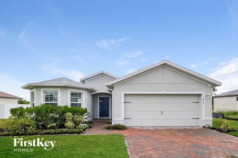 a white house with a garage door and a lawn