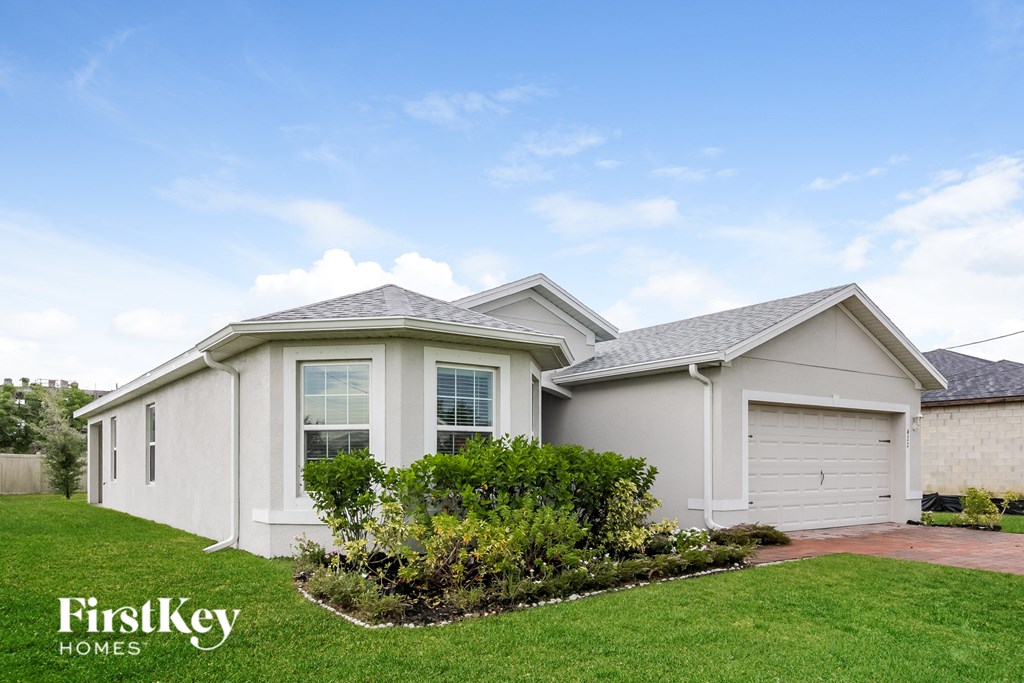 a small white house with a lawn and a driveway