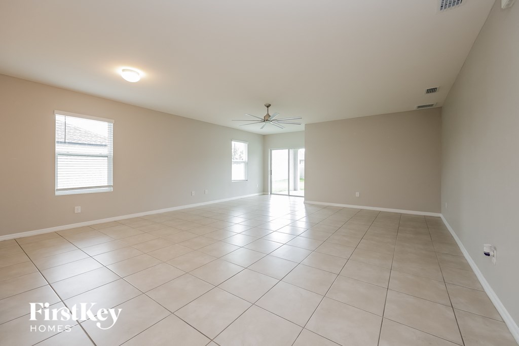 an empty living room with tiled floors and a ceiling fan