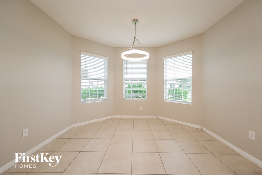 an empty dining room with windows and a ceiling light