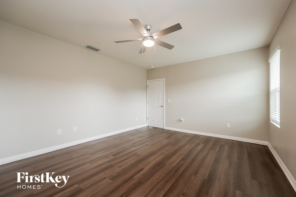 the spacious living room with hardwood flooring and a ceiling fan