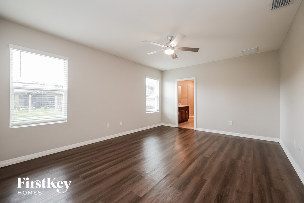 an empty living room with wood floors and a ceiling fan
