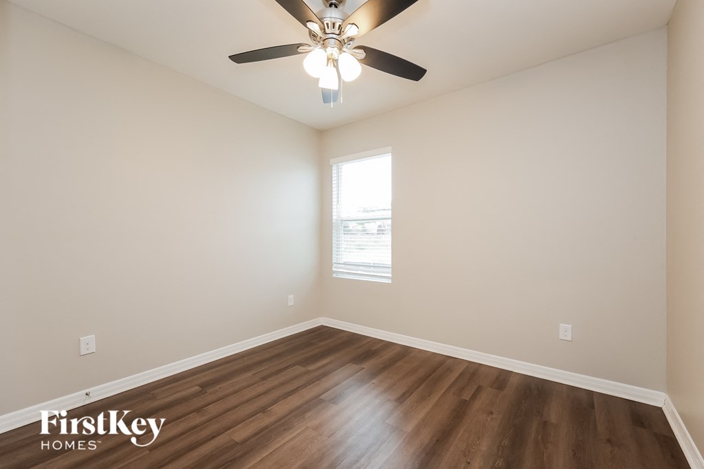 the spacious living room with hardwood flooring and a ceiling fan