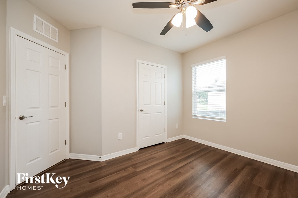 a bedroom with hardwood flooring and a ceiling fan