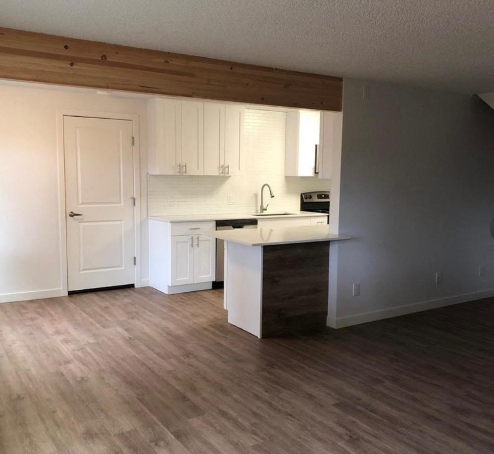 an empty kitchen with wooden floors and white cabinets