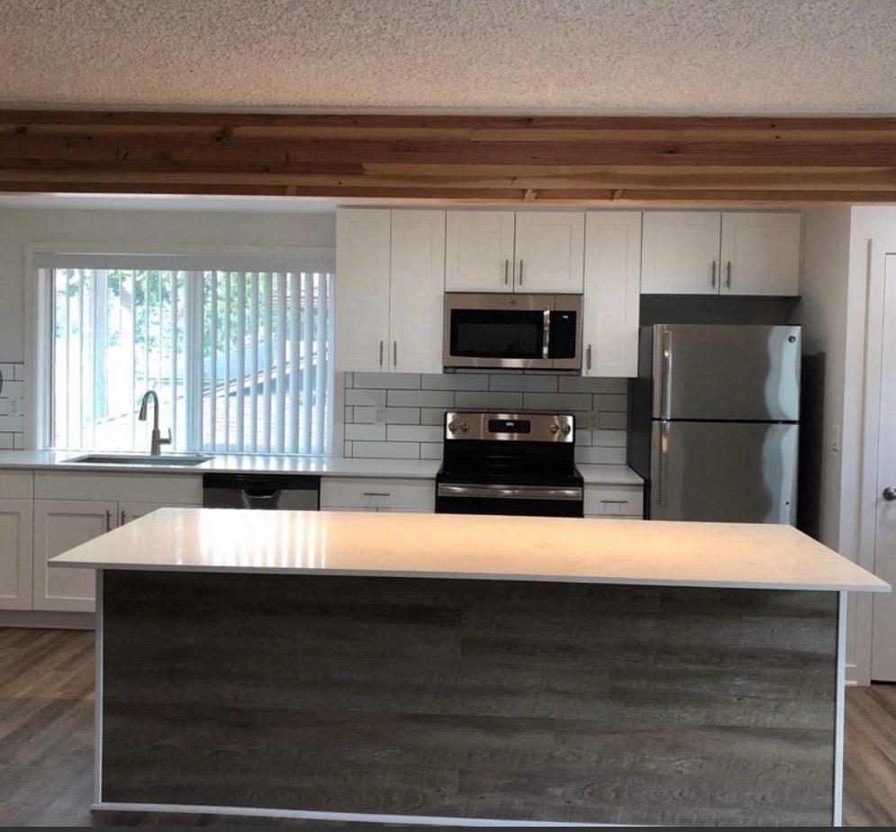 an empty kitchen with white cabinets and a counter top
