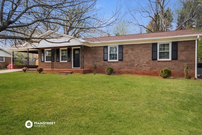 a brick house with a green lawn and a tree