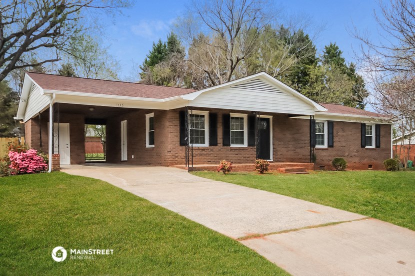 a small brick house with a sidewalk in front of it