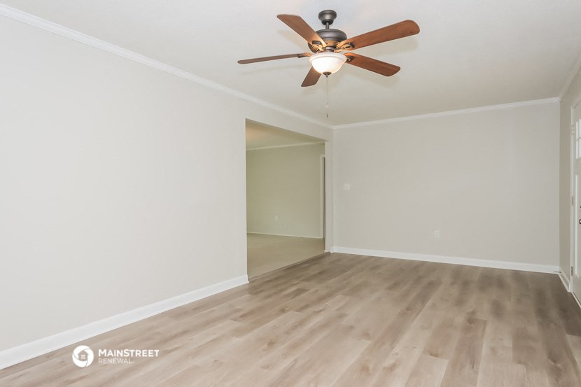 an empty living room with wood floors and a ceiling fan