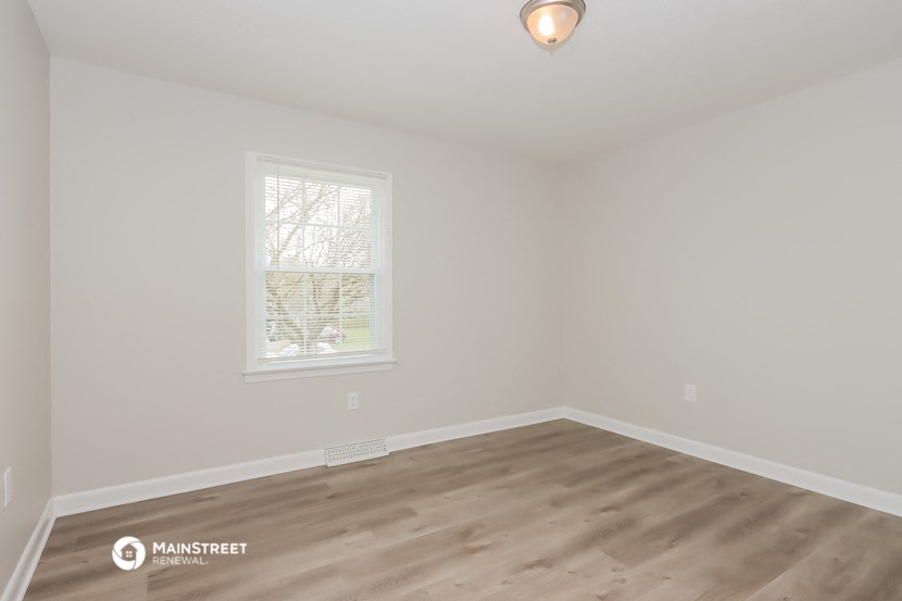 the living room of a house with wooden floors and a window