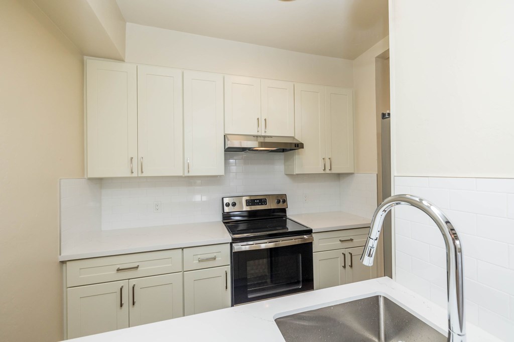 a kitchen with white cabinets and a sink and a stove
