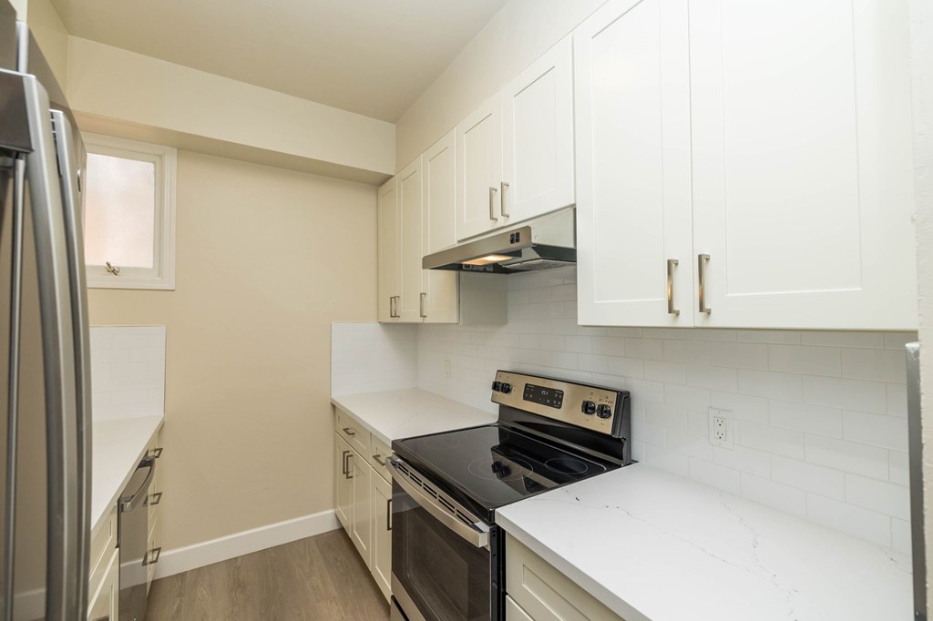 a kitchen with white cabinets and a stove and a refrigerator