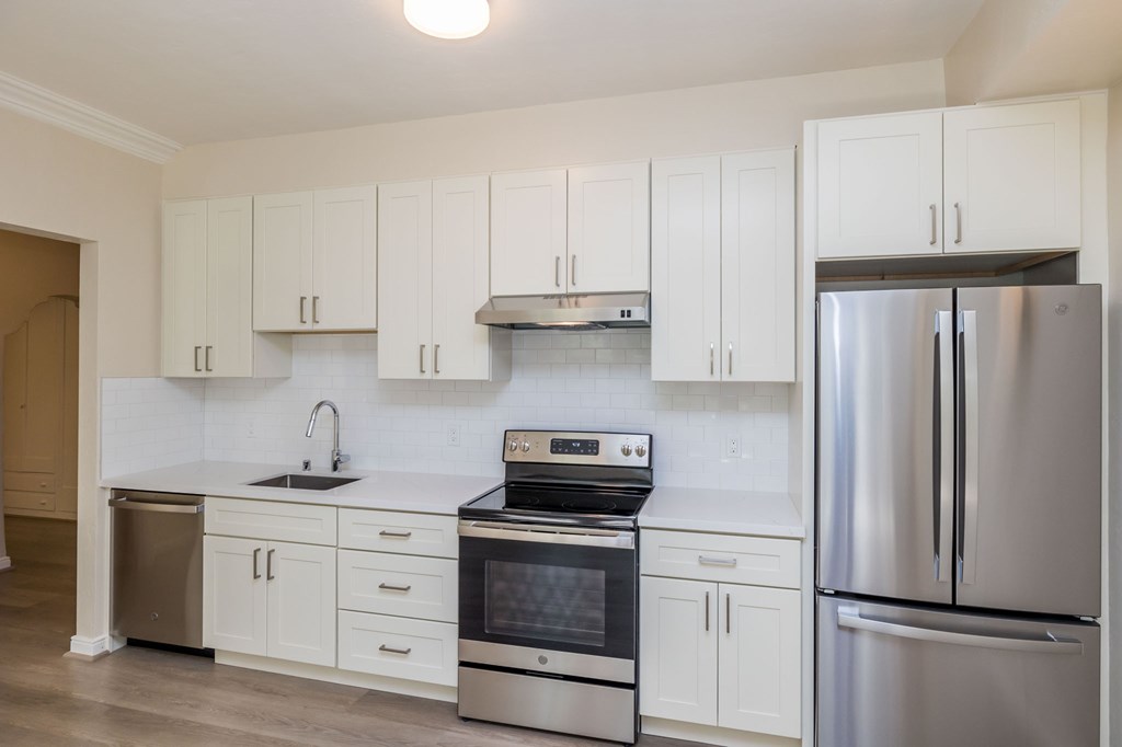a white kitchen with stainless steel appliances and white cabinets