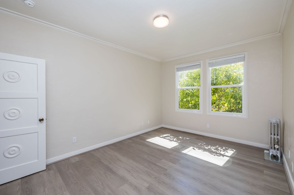 an empty room with a white door and two windows
