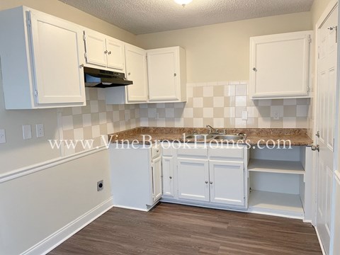 A kitchen with white cabinets and a checkered backsplash.