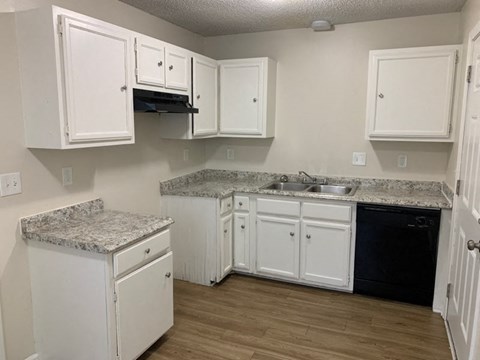 A kitchen with white cabinets and a granite countertop.