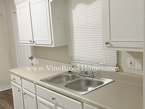 a small kitchen with a sink and white cabinets