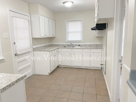 A kitchen with white cabinets and a marble countertop.