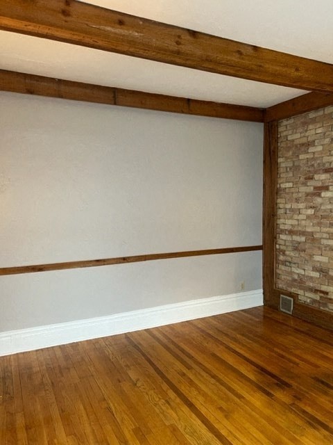 an empty living room with wood floors and a brick wall