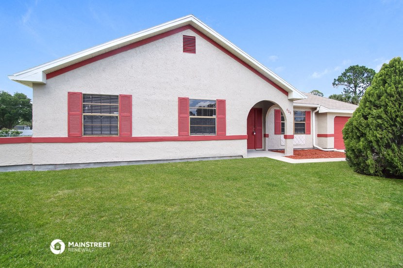 a white house with red shutters and a green lawn