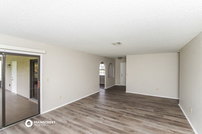 the living room and dining room of an apartment with wood floors and white walls