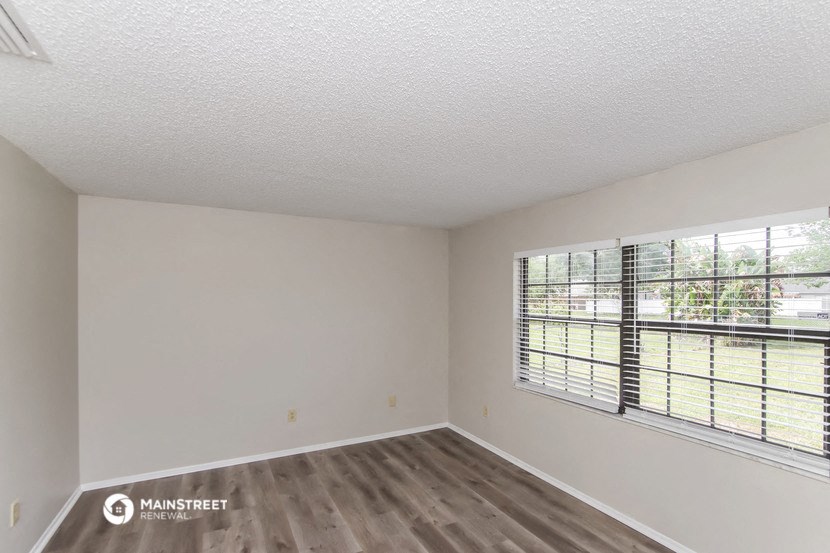 the spacious living room of an apartment with a large window