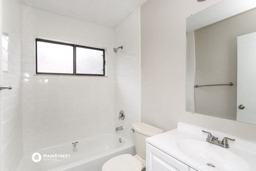 a white bathroom with a tub and a sink and a toilet
