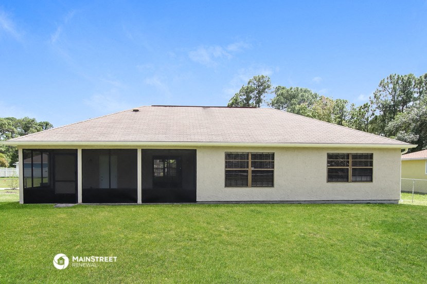 front view of a ranch style home with lawn and trees