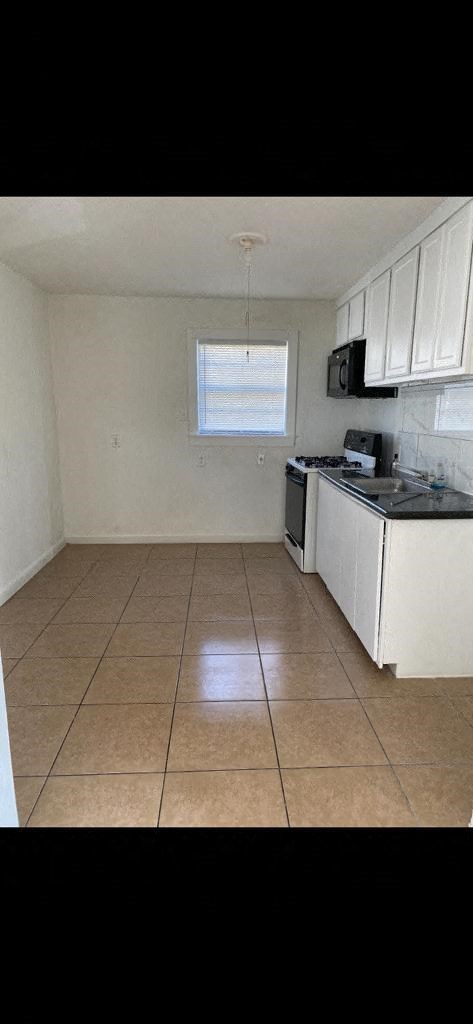 a kitchen with a tiled floor and white cabinets
