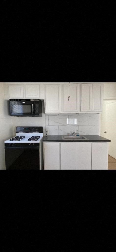 a kitchen with white cabinets and a stove and a microwave