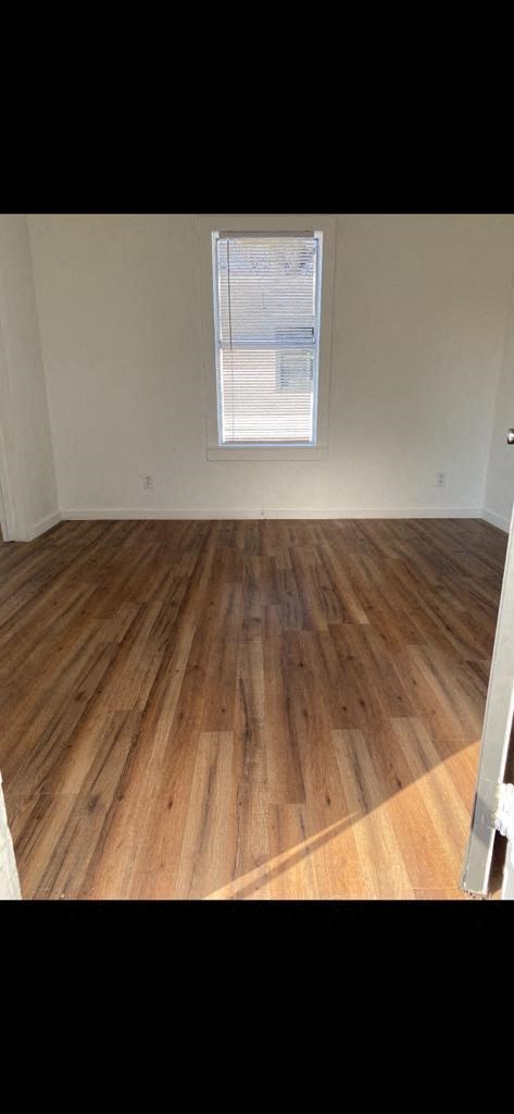 an empty room with wooden floors and a window