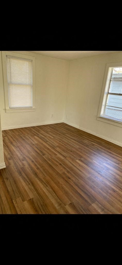 an empty room with a wooden floor and two windows
