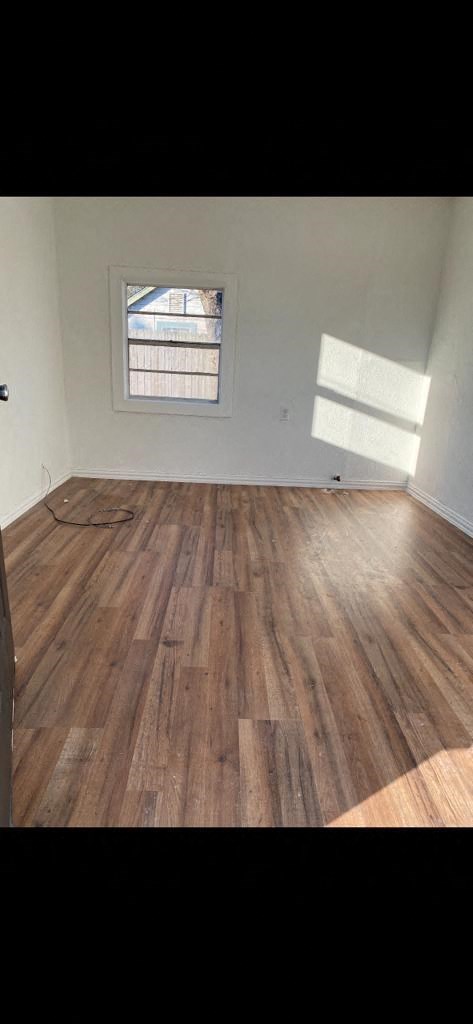 an empty room with wooden floors and a window