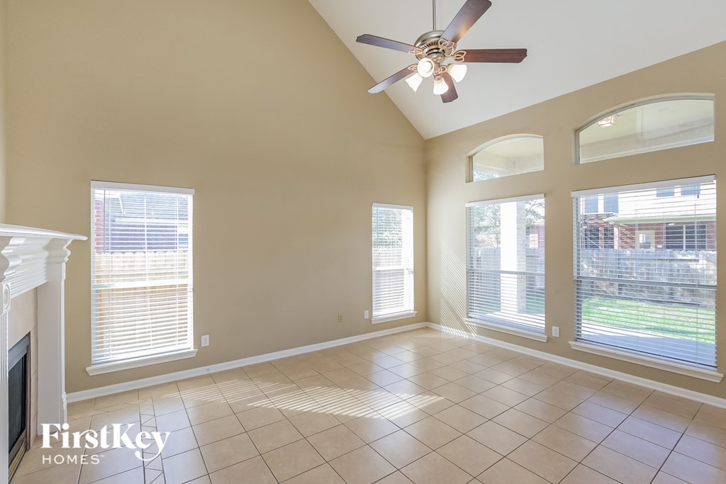 A spacious room with a fireplace and a ceiling fan.