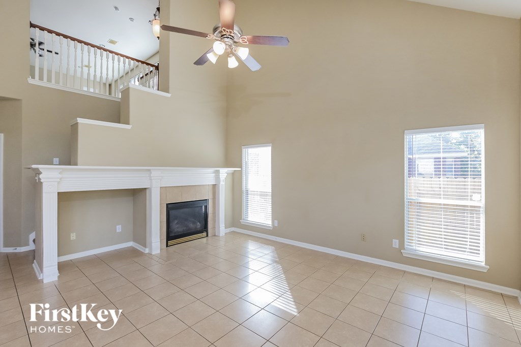 A spacious living room with a fireplace and a ceiling fan.