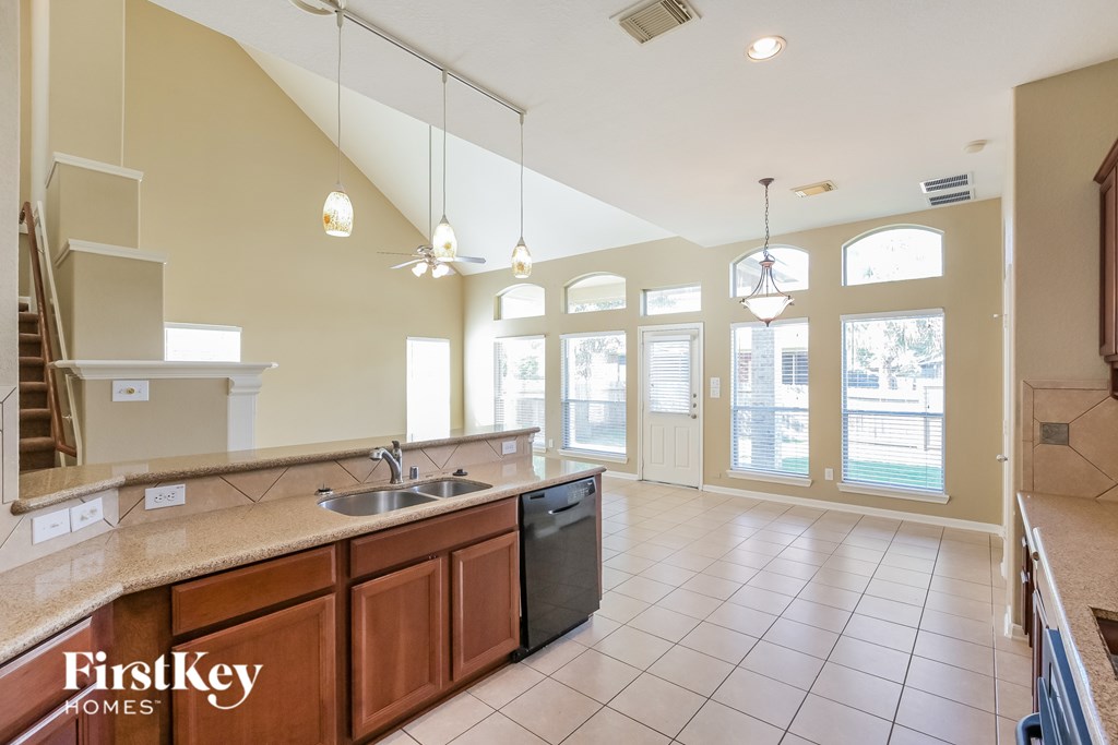 A kitchen with a sink, stove, and cabinets.