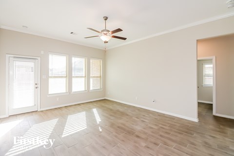 A spacious room with a ceiling fan and wooden flooring.