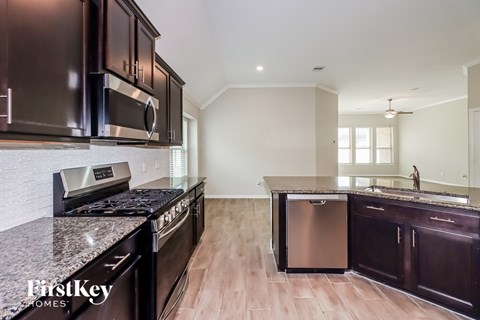 A kitchen with dark brown cabinets and a granite countertop.