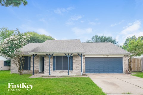 A house with a garage door and a tree in front of it.